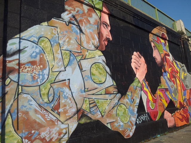 Sehr farbenfrohes Graffiti zweier armdrückender Künstler - gut gelungen sind vor allem die Gesichtspartien.